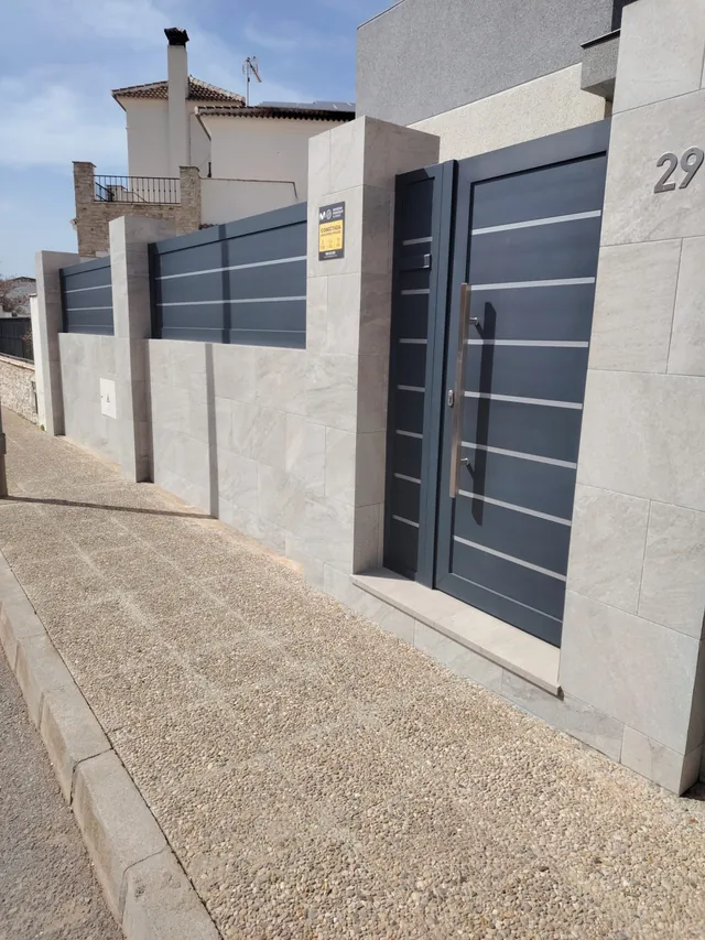Cerramiento exterior y acceso renovados por Reformas Aurelio